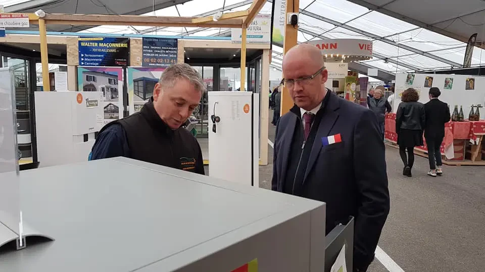 Homme en tenue de travail ajustant un radiateur blanc dans un intérieur résidentiel près d'une fenêtre