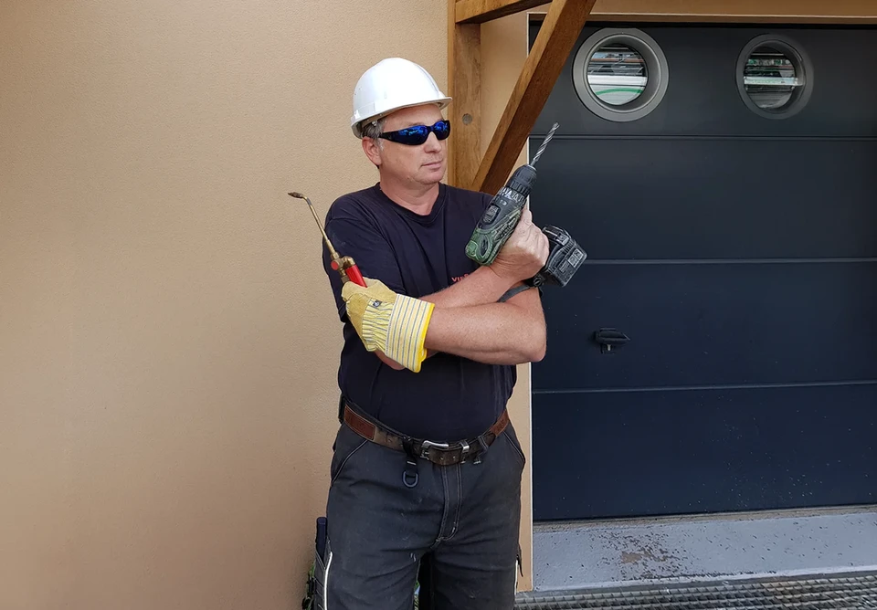 Technicien en plomberie travaillant dans une chaufferie résidentielle, ajustant une canalisation avec une clé à molette rouge