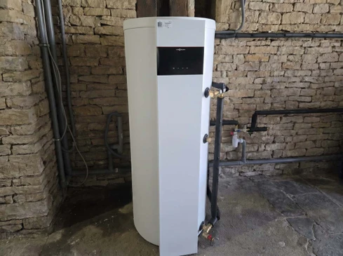 Chauffe-eau thermodynamique blanc ou gris clair install&eacute; dans une chaufferie ou buanderie moderne d'une maison r&eacute;sidentielle. L'&eacute;quipement doit &ecirc;tre clairement identifiable comme une pompe &agrave; chaleur pour eau chaude sanitaire (technologie thermodynamique avec &eacute;vaporateur visible ou design caract&eacute;ristique), install&eacute; contre un mur clair dans un int&eacute;rieur fonctionnel et bien &eacute;clair&eacute;, montrant la qualit&eacute; et la performance de la solution.