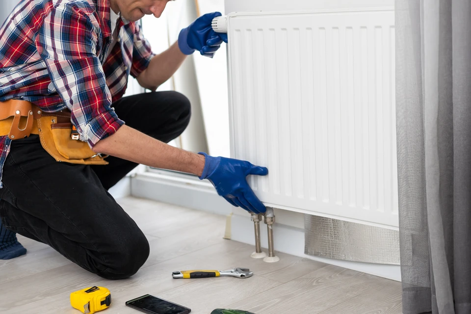 Ouvrier en casquette installant un support métallique de climatisation sur mur intérieur