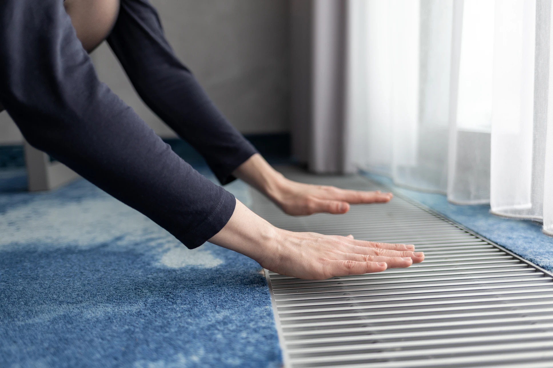 Homme en t-shirt gris ajustant un robinet thermostatique de radiateur dans un intérieur résidentiel